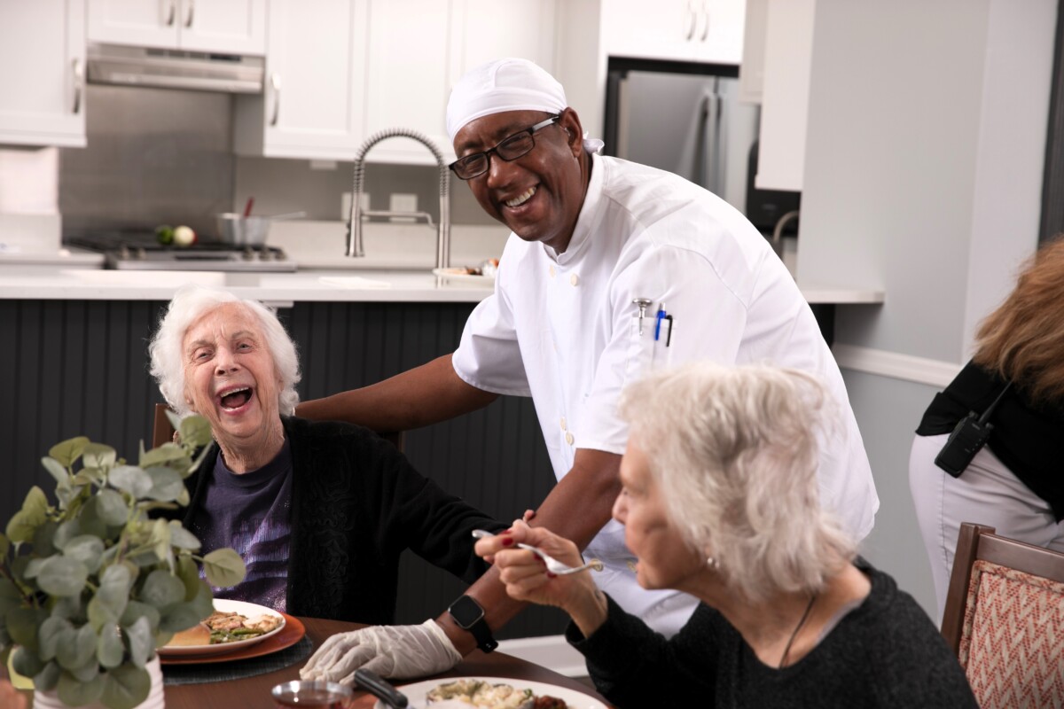 Chef and two residents laughing at dining table