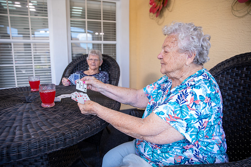 two elderly women playing a game of cards at a table
