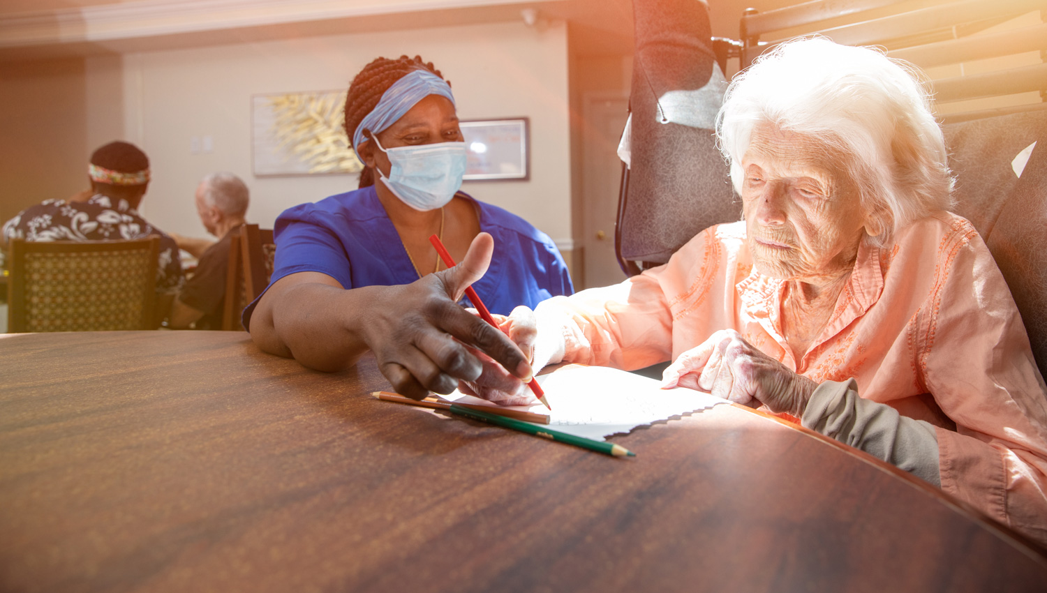 memory care resident writing with caregiver