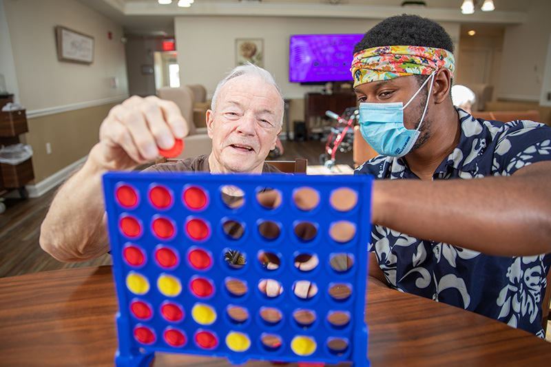 senior care resident playing connect 4 with care provider