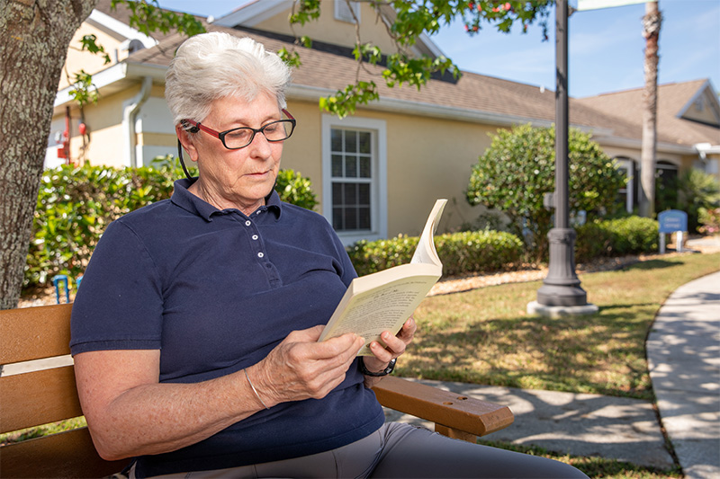 Alzheimer's care facility resident reading outside